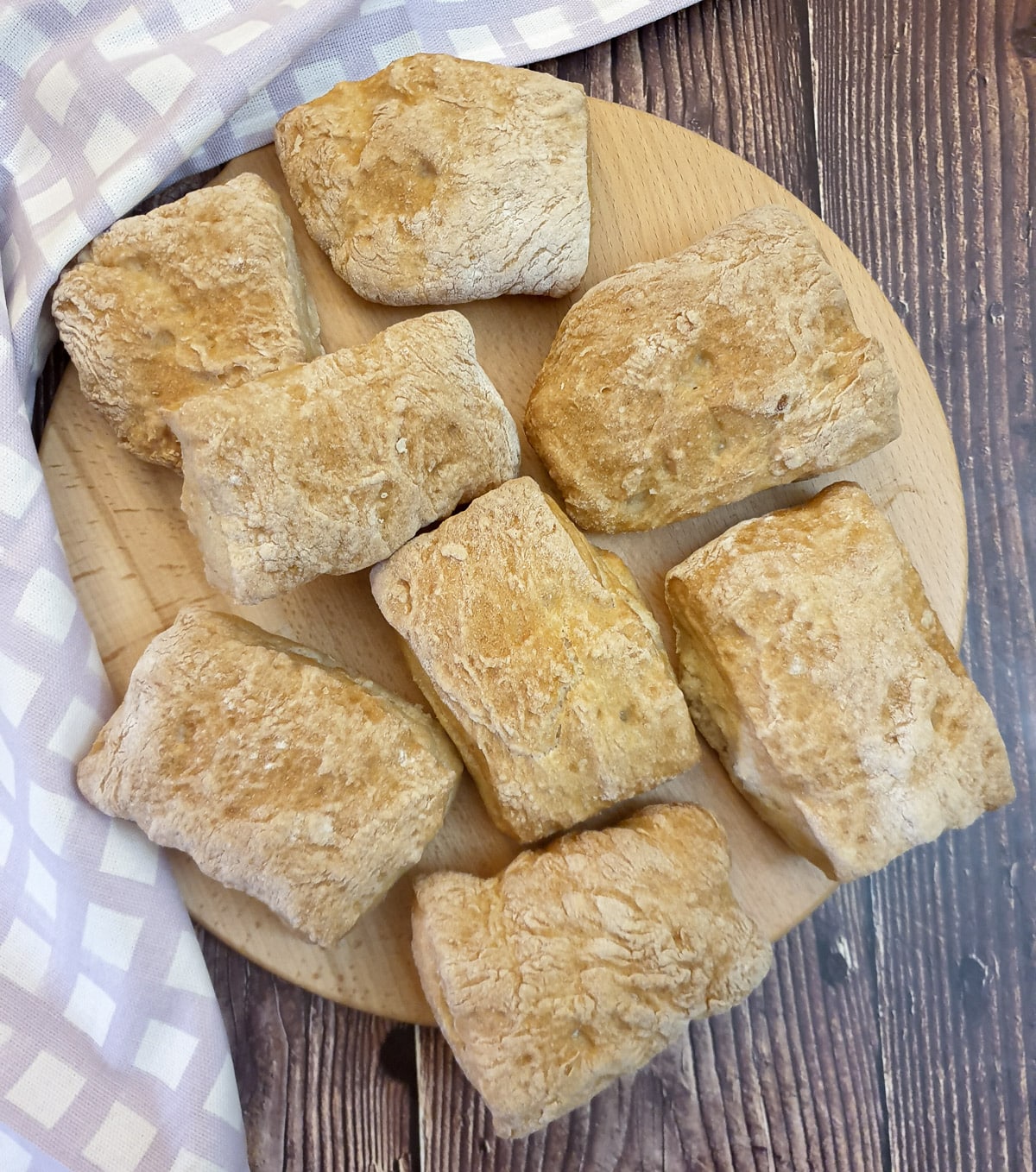 8 ciabatta rolls on  wooden board.