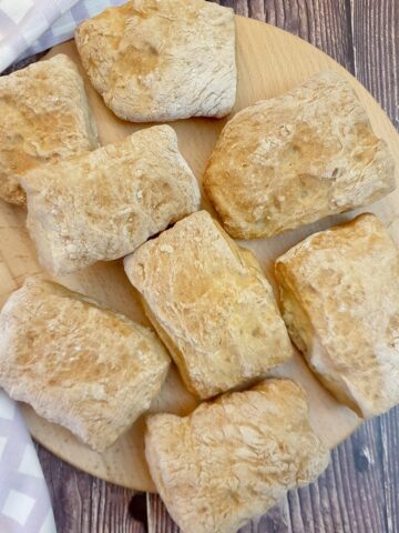 8 ciabatta rolls on wooden board.