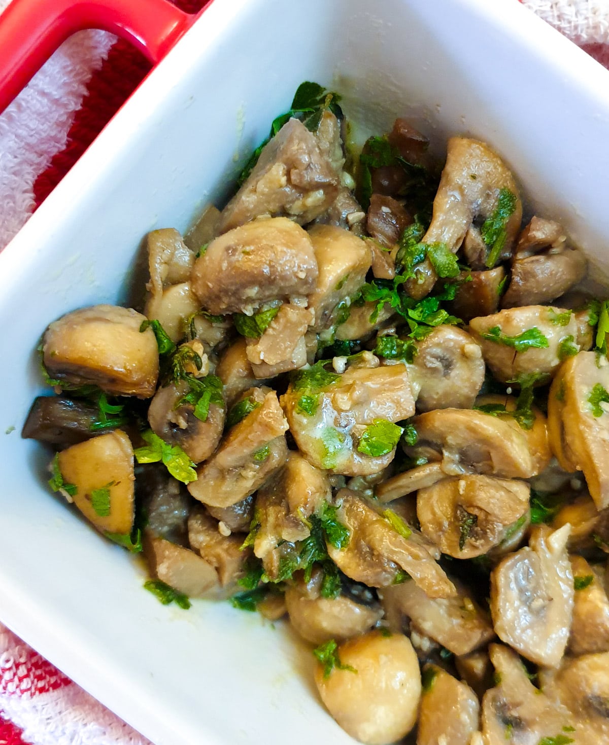 Garlic mushrooms garnished with parsley in a white dish.