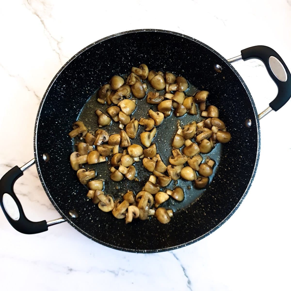 A frying pan containing mushrooms that have completely browned.