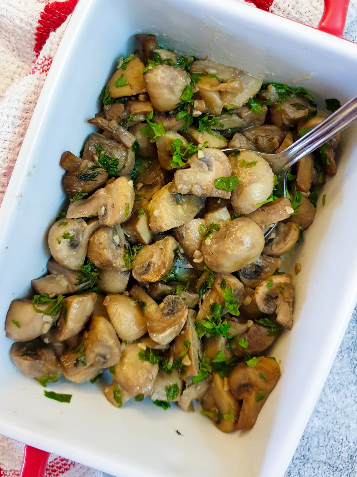 Overhead shot of a serving dish of mushrooms with a spoon.