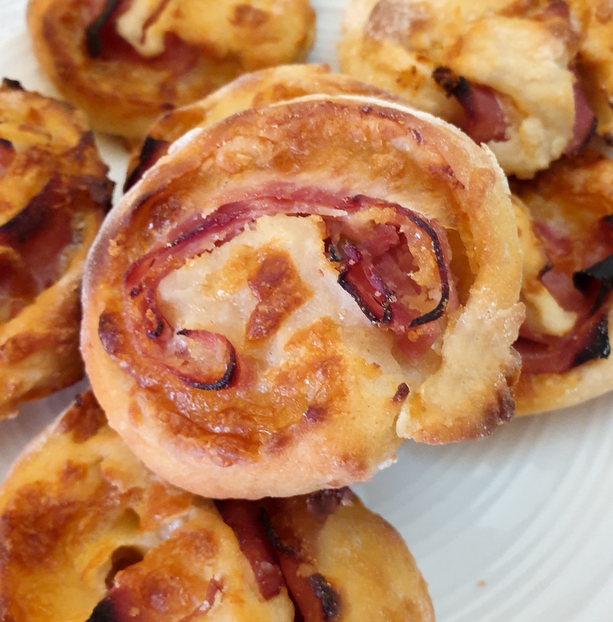 A pile of ham and cheese pinwheels on a plate.