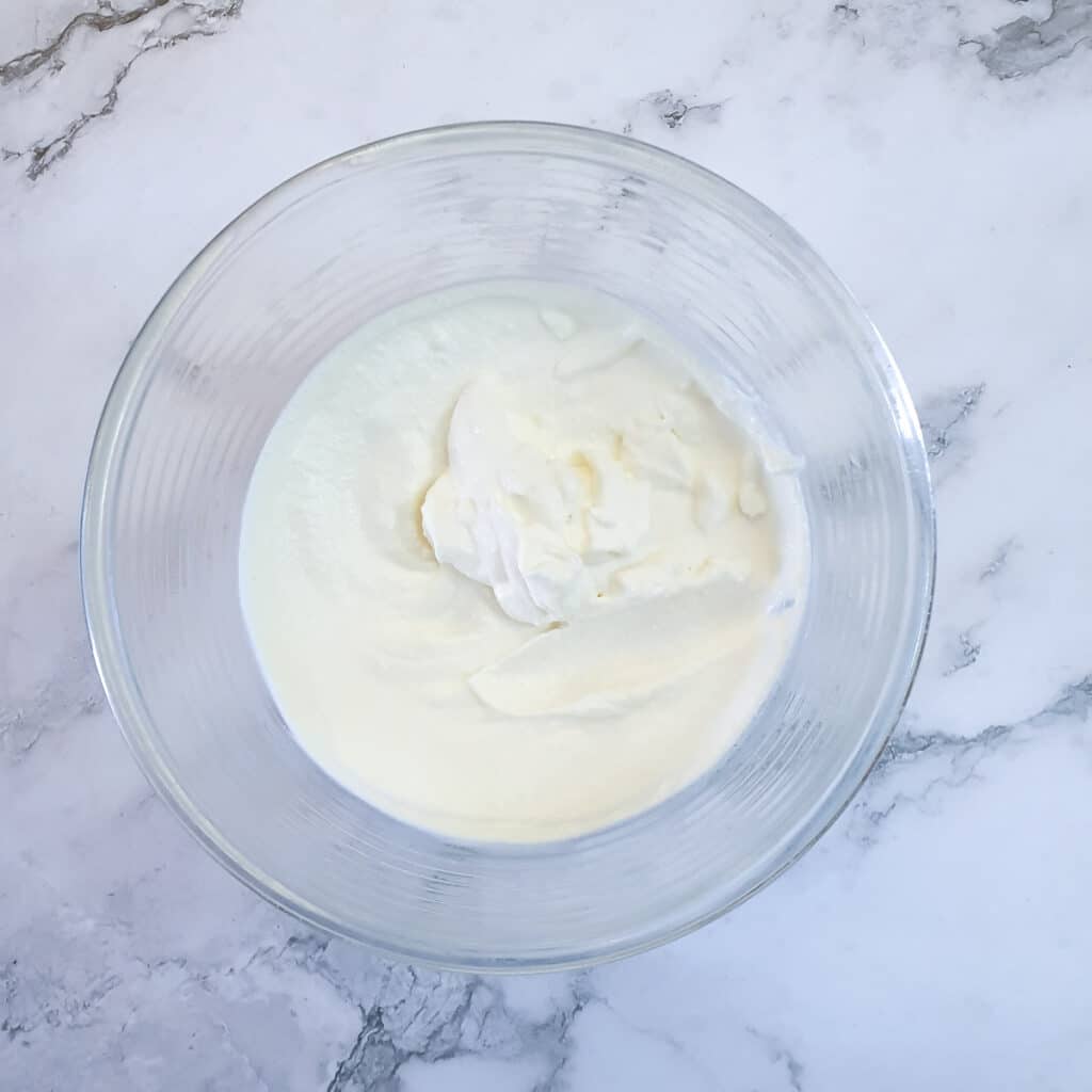 Stiffly whipped cream in a glass bowl.