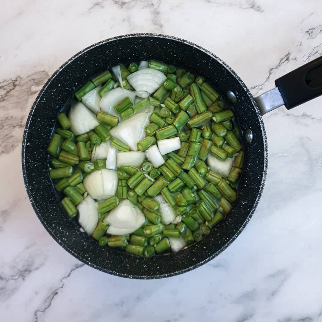 Beans, potatoes and onions in a pan of water, ready to be boiled.