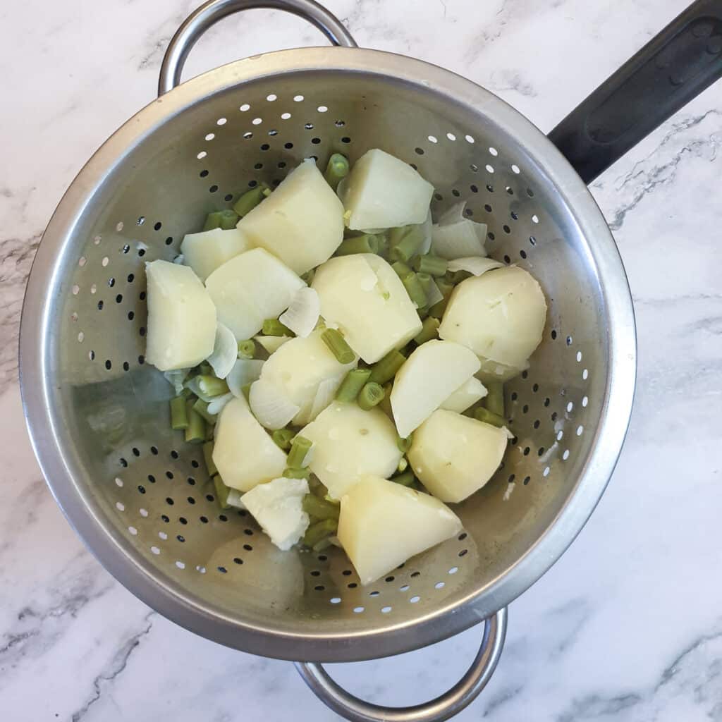 Potatoes, beans and onions in a colander.