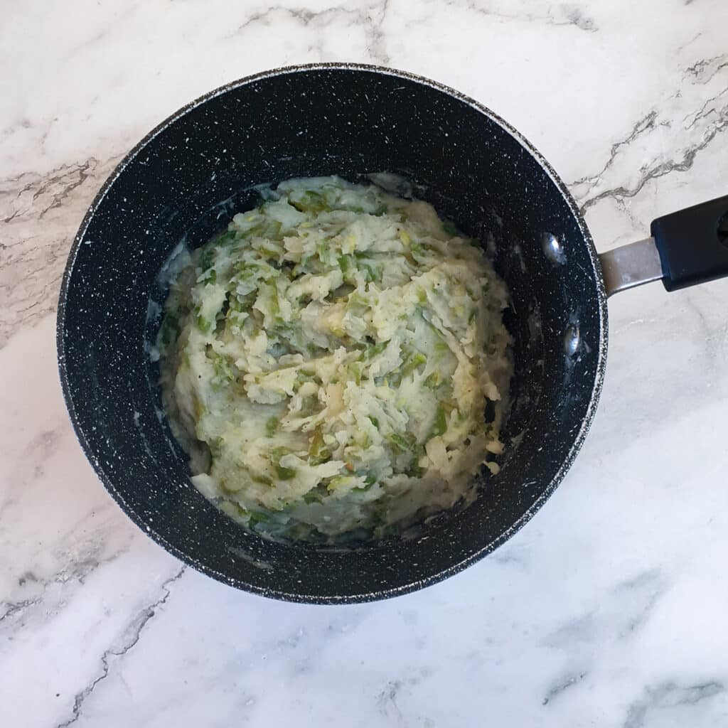 A saucepan of beans mashed with potatoes and onions.