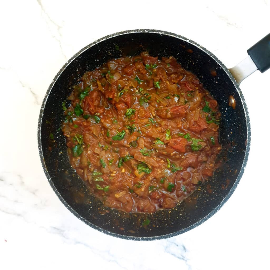 Chopped organo stirred into a pan of homemade tomato sauce.