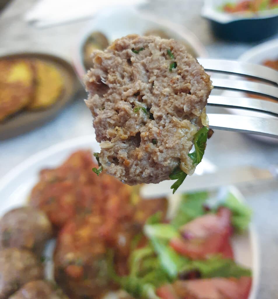 Half a lamb meatball on a fork showing the juicy inside.