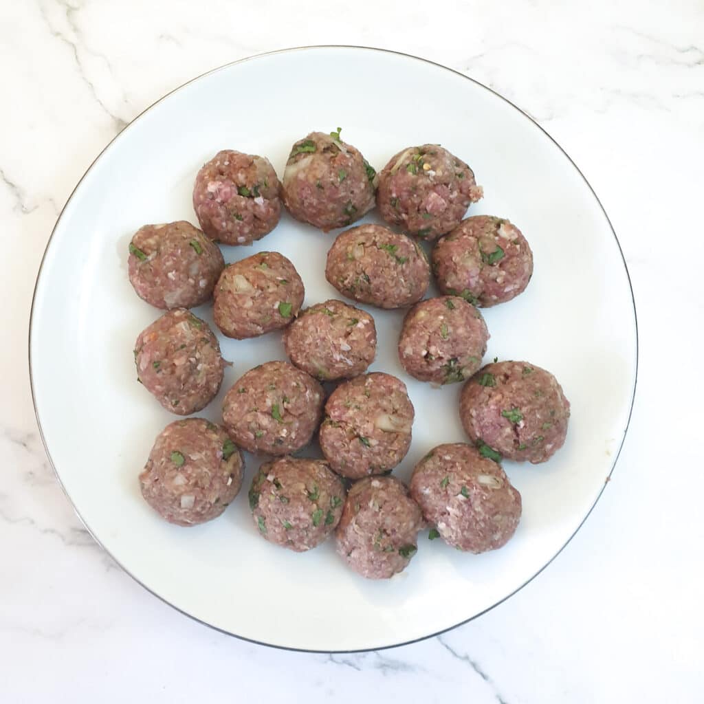 A pile of rolled meatballs on a plate.