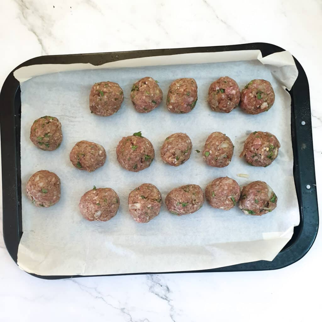 Unbaked meatballs on a baking tray.