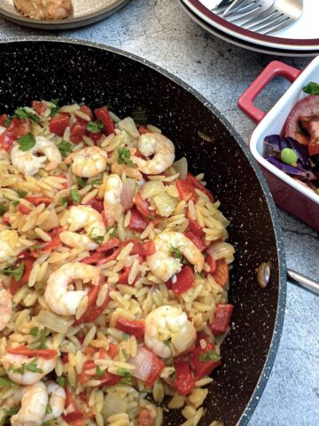 Roasted red pepper pasta with prawns in a frying pan.