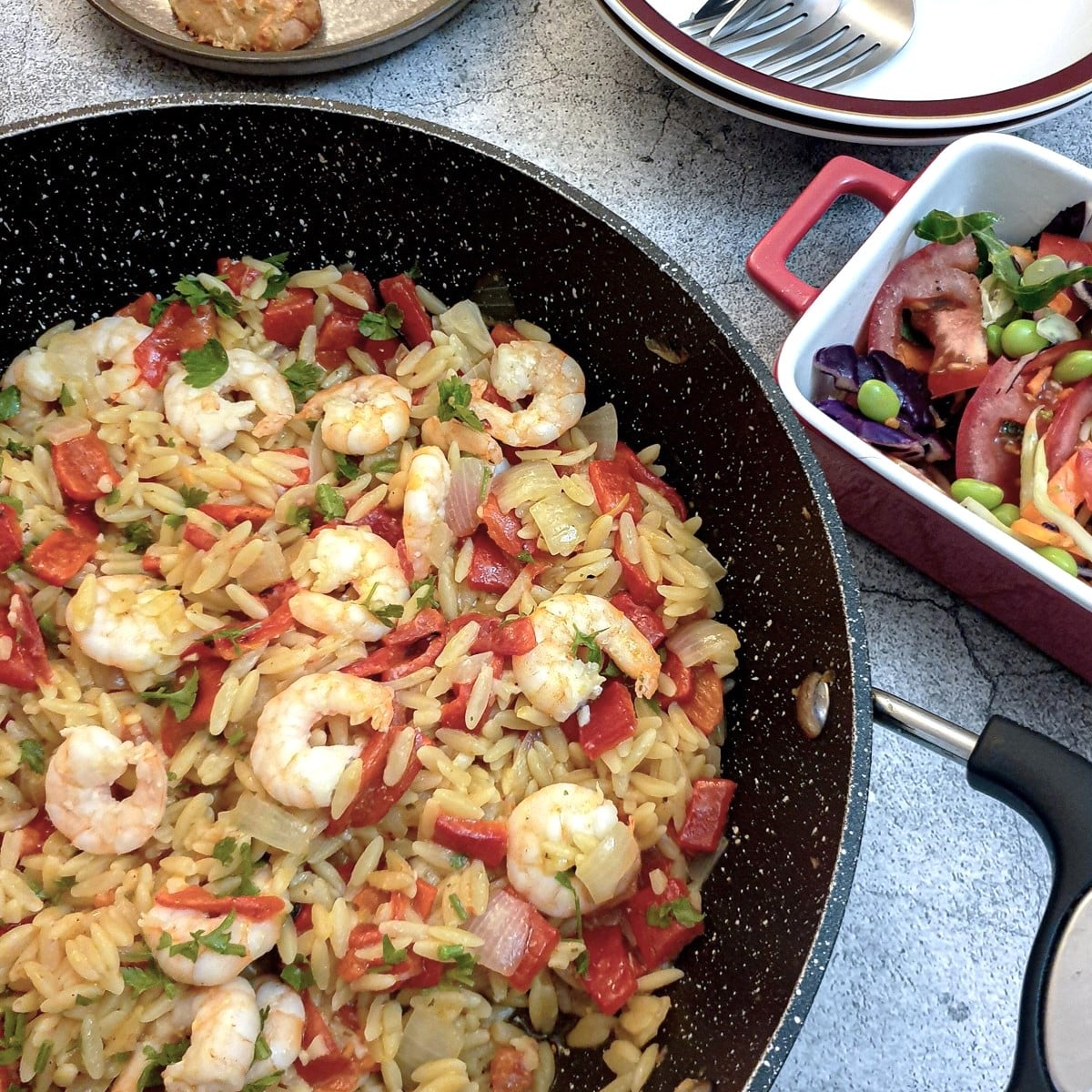 Roasted red pepper pasta with prawns in a frying pan.