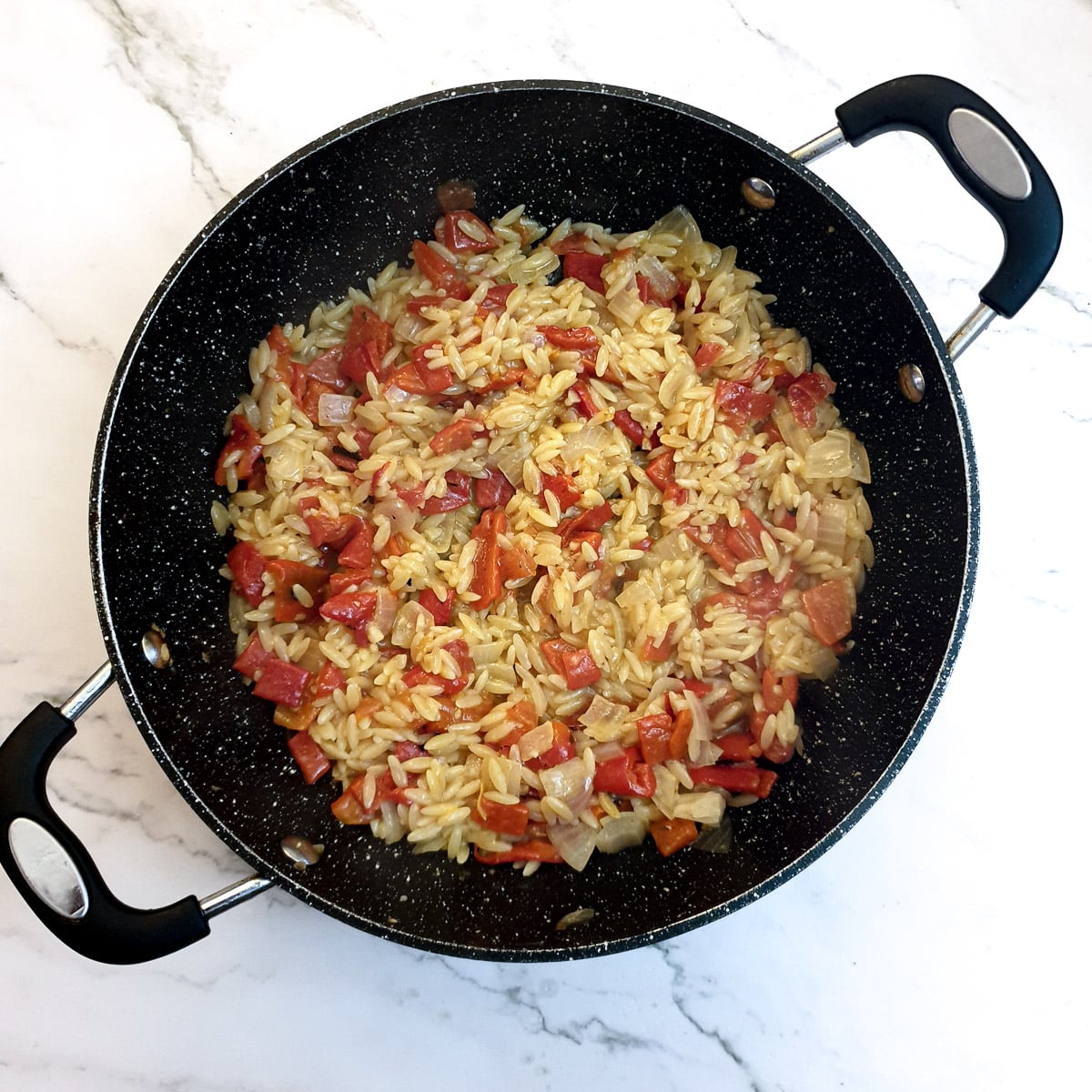  Red pepper pasta in a frying pan showing how the liquid has been absorbed into the pasta.