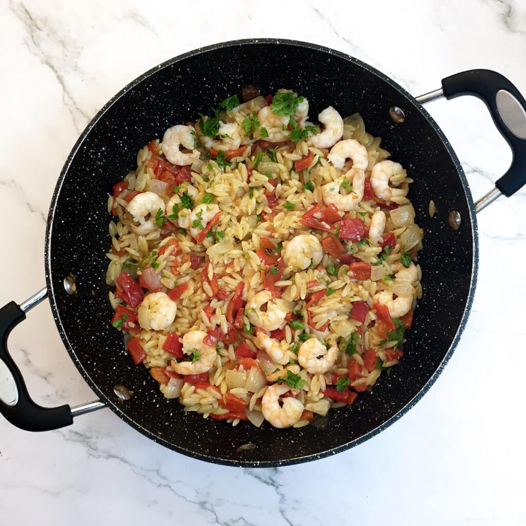 Red pepper pasta with prawns mixed with parsley.
