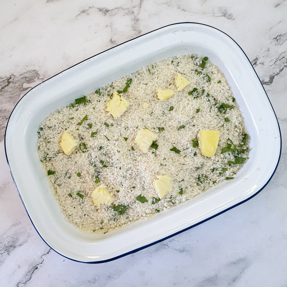 Salmon and asparagus gratin covered in breadcrumbs and ready to be baked.