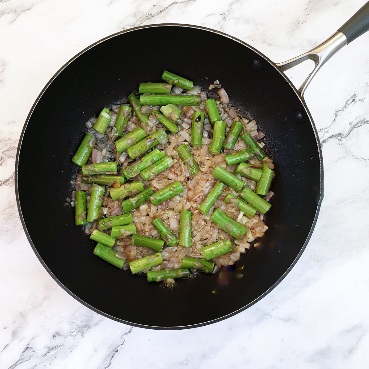 Chopped asparagus stalks frying with shallots.