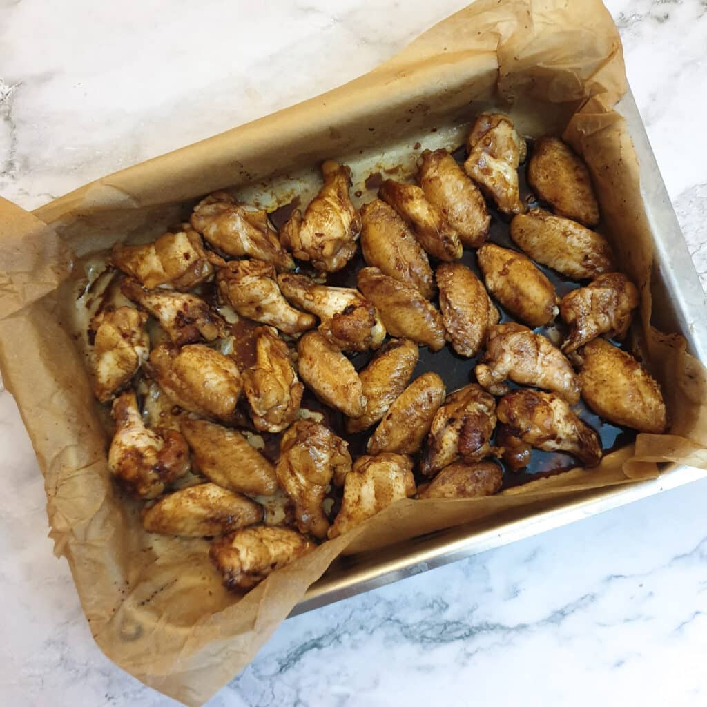 Chicken wings turned skin-side up in a baking dish.