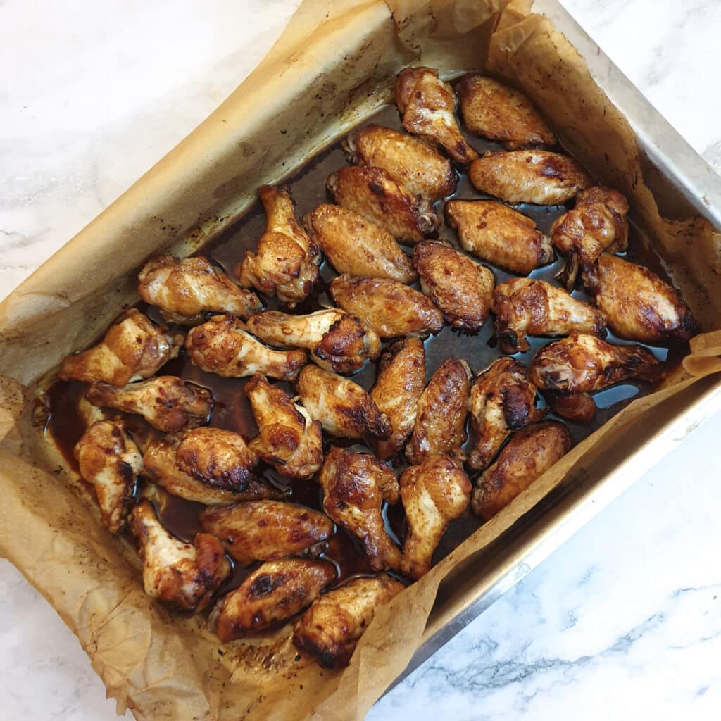 Cooked sticky chicken wings in a baking dish.