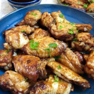 Close up of a blue dish containing honey-glazed chicken wings.