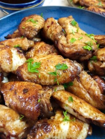 Close up of a blue dish ontaining sticky chicken wings.