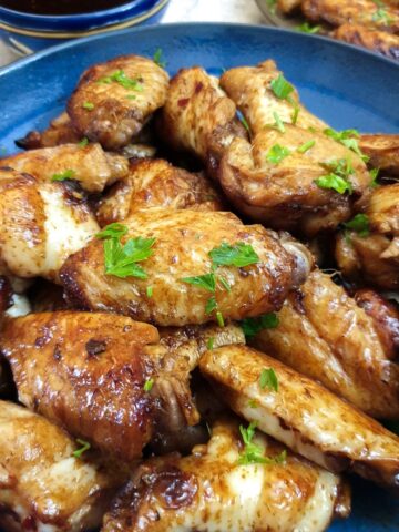 Close up of a blue dish containing honey-glazed chicken wings.