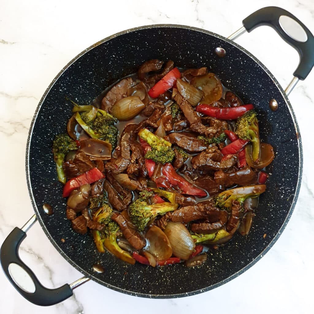 A frying pan holding the coooked Szechuan beef stirfry.