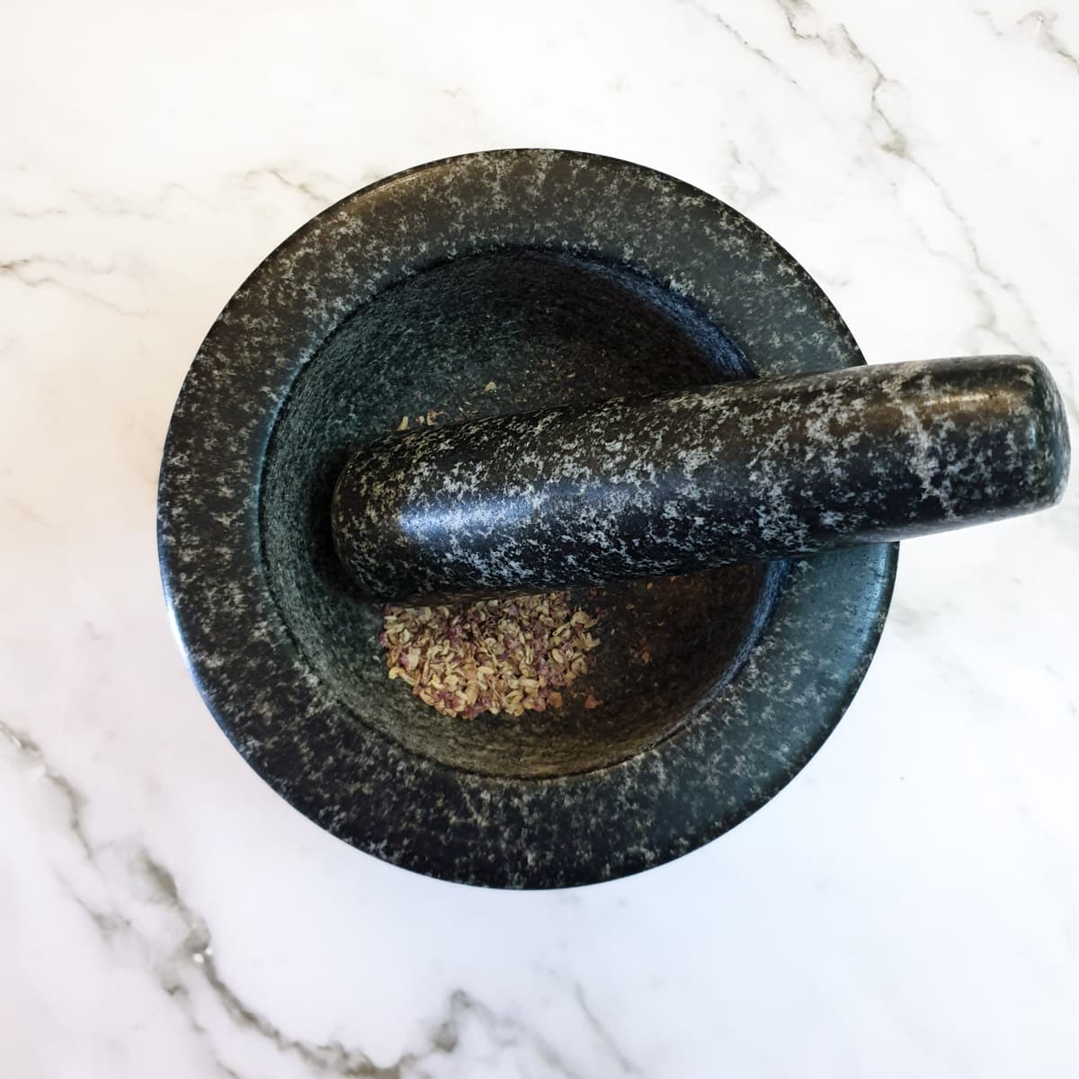 A mortar and pestle with ground up Szechuan peppercorns.