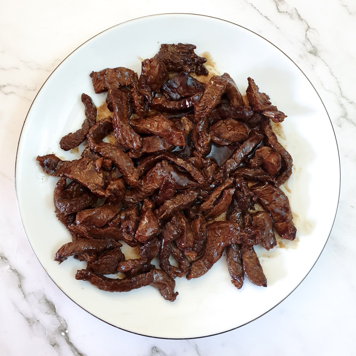 Fried beef strips on a white plate.