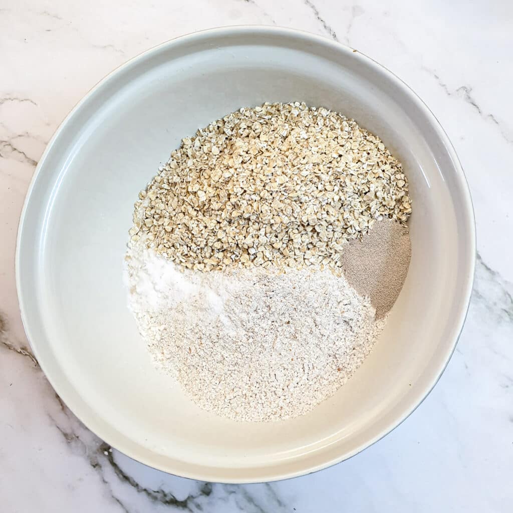 Dry ingredients for seeded bread rolls in a mixing bowl.