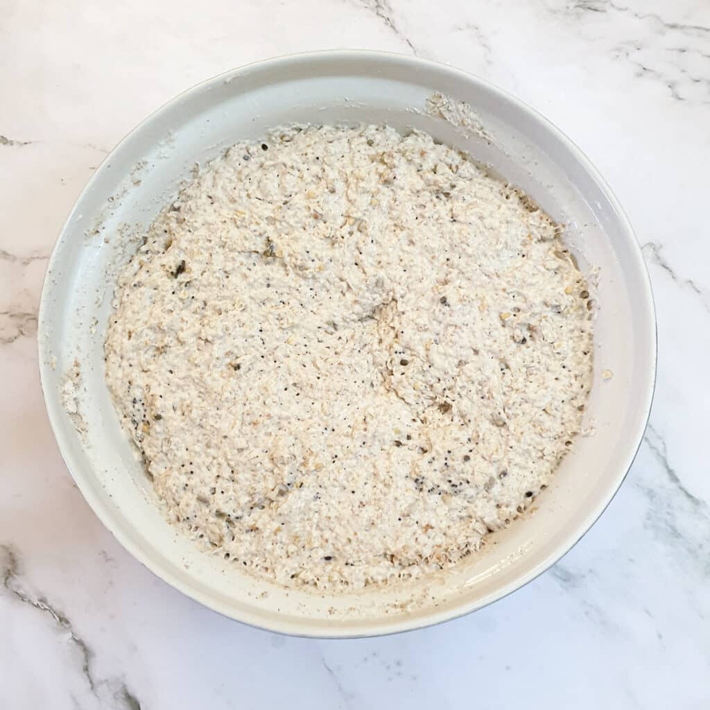 Seeded breadroll dough that has doubled in size in a mixing bowl.