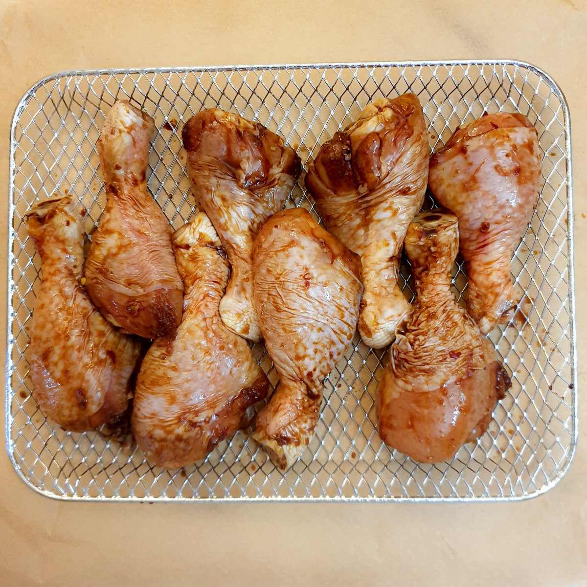 8 chicken drumsticks arranged on an air fryer oven rack.