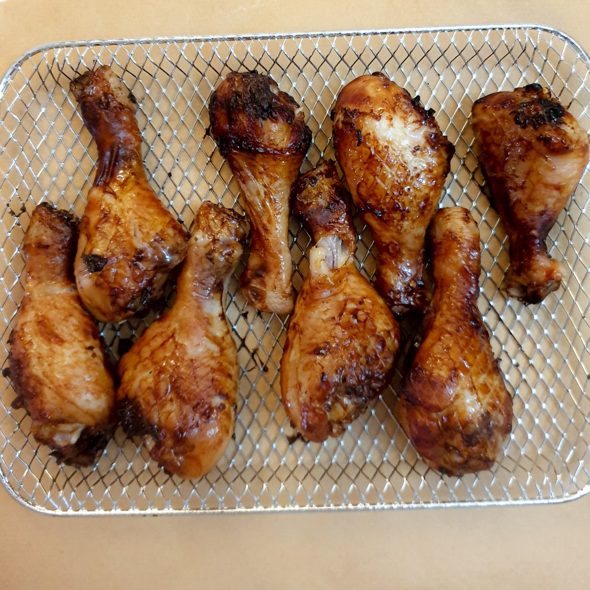 8 chicken drumsticks on an air fryer oven rack after being cooked.