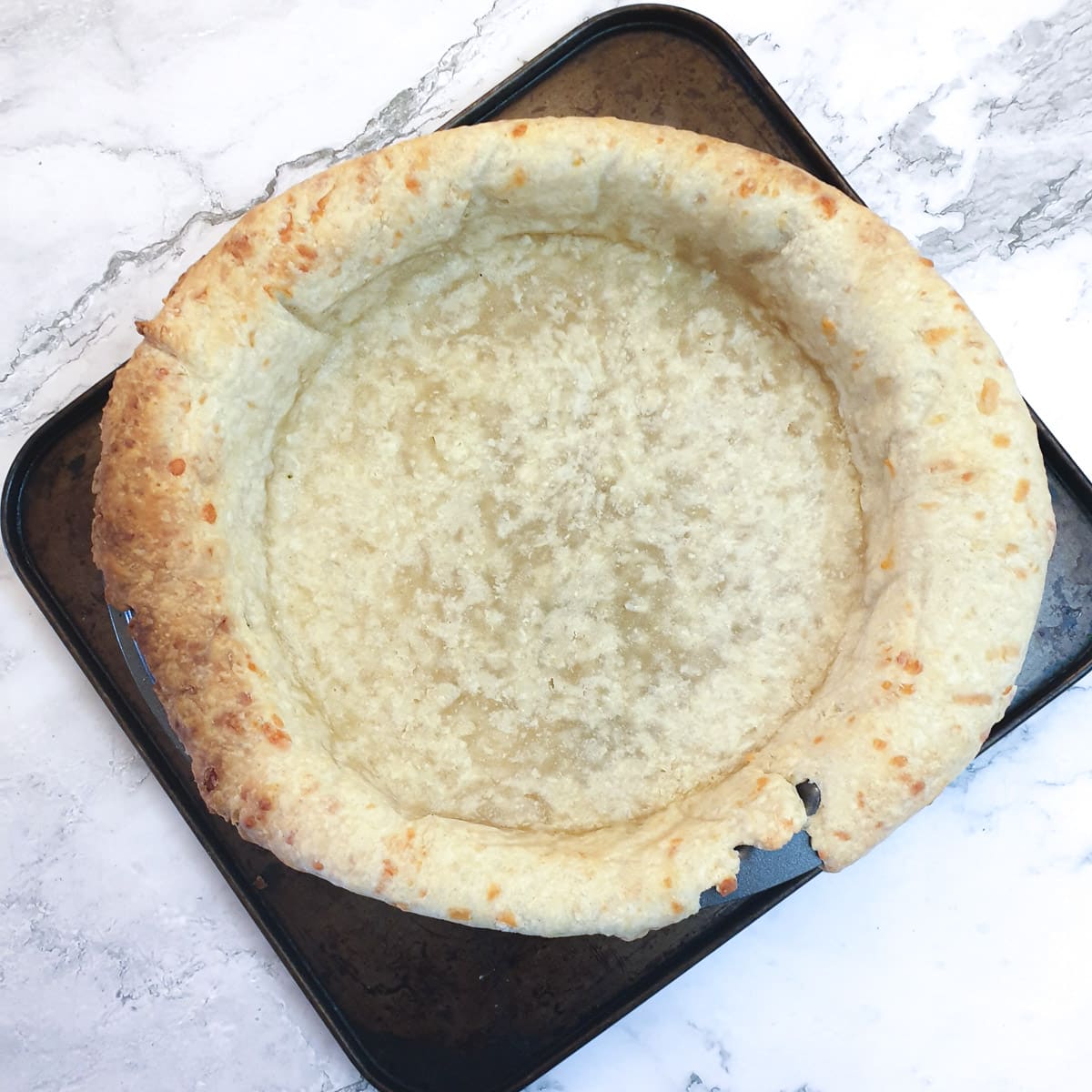 A part-baked pastry case in a flan dish.