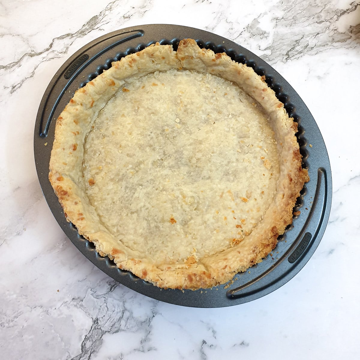 A baked cheese pastry shell in a flan dish.