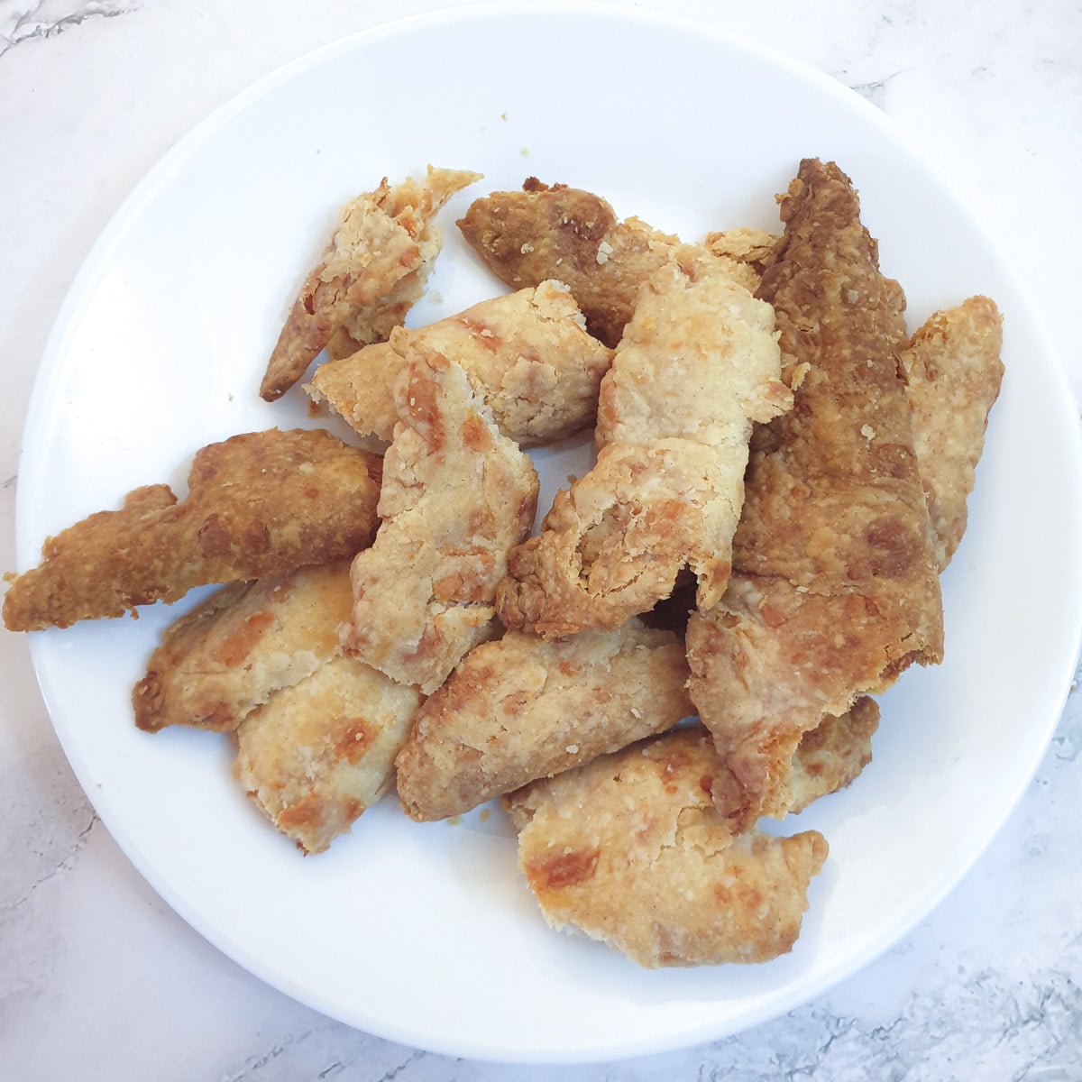 Pieces of baked pastry off-cuts on a white plate.