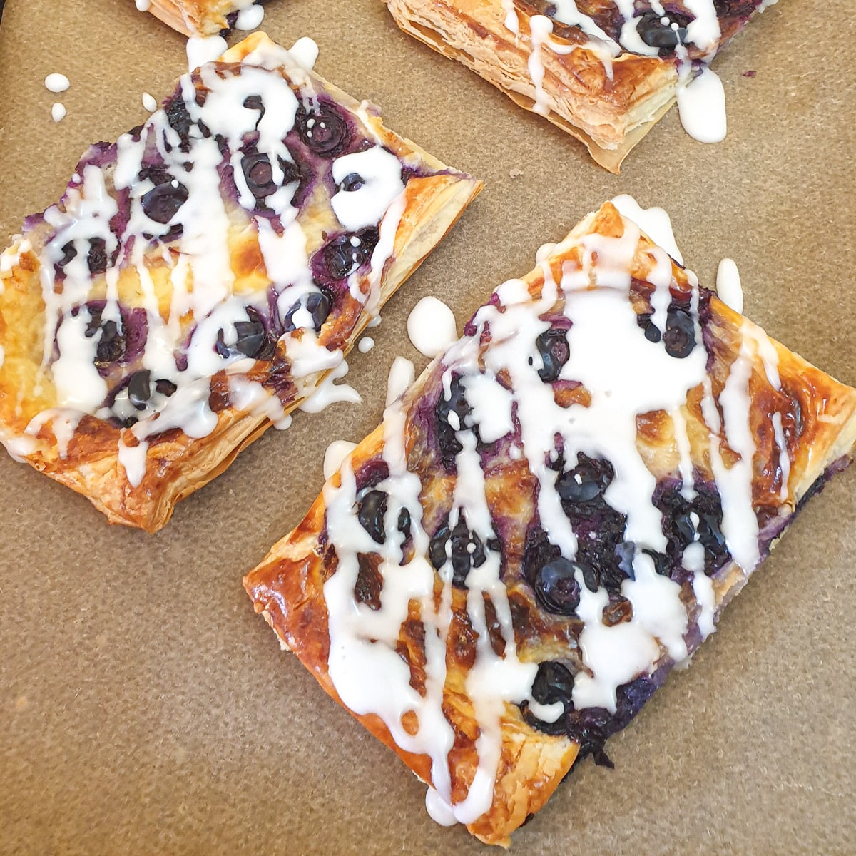 Overhead shot of 2 Danish pastries drizzled with icing sugar glaze.