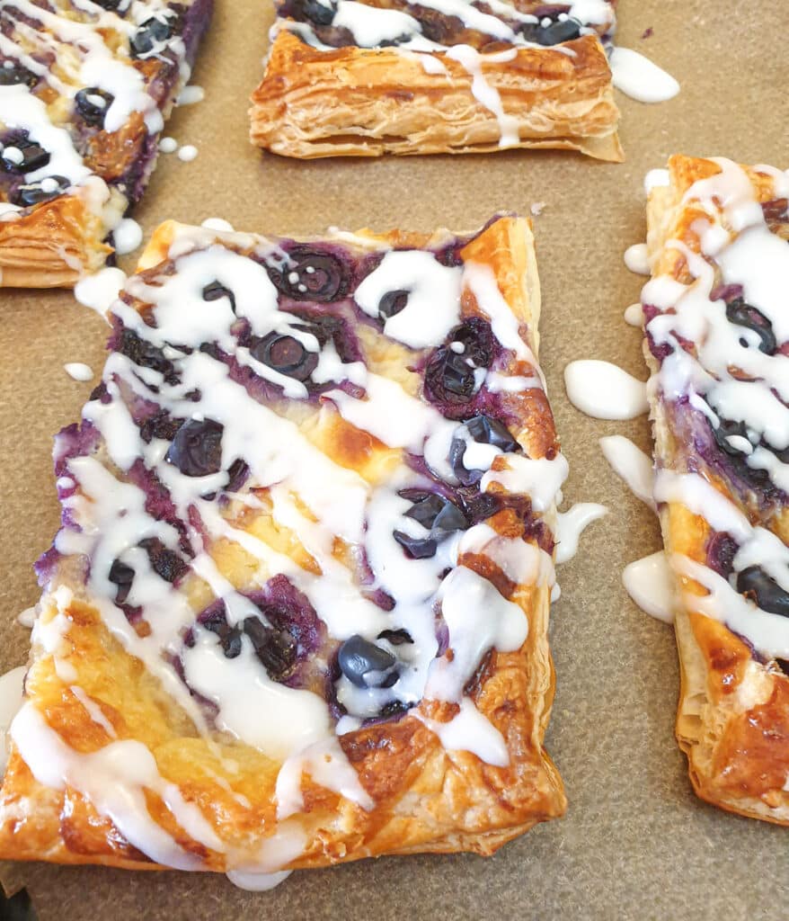 Blueberry cream cheese Danish pastries drizzled with icing sugar glaze.