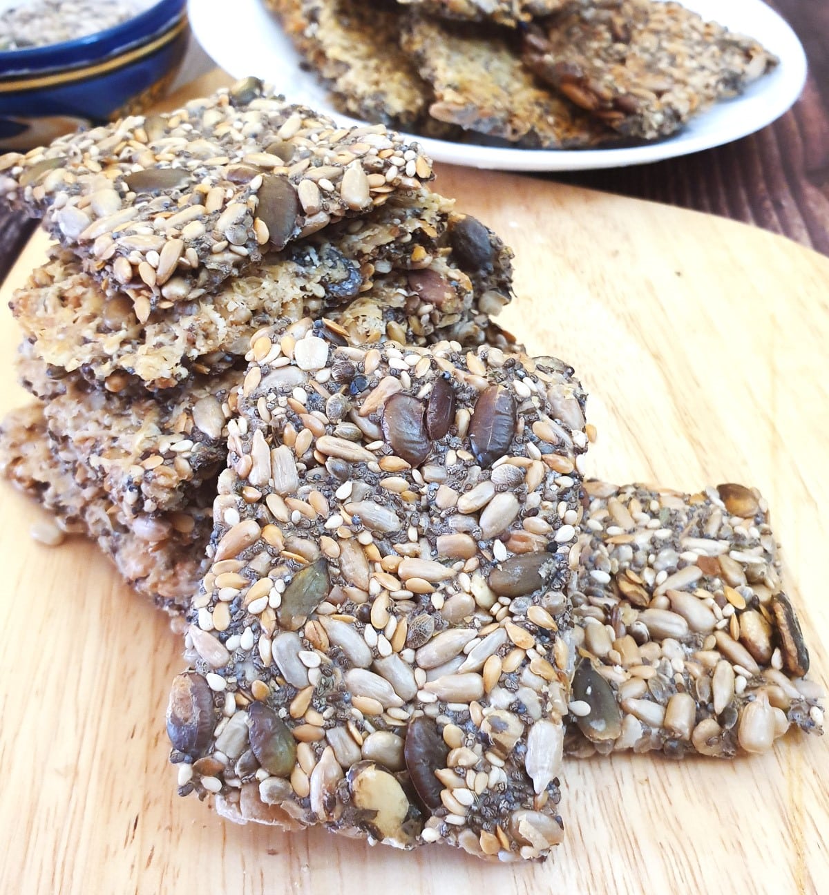 A pile of crispy seeded crackers on a wooden board.