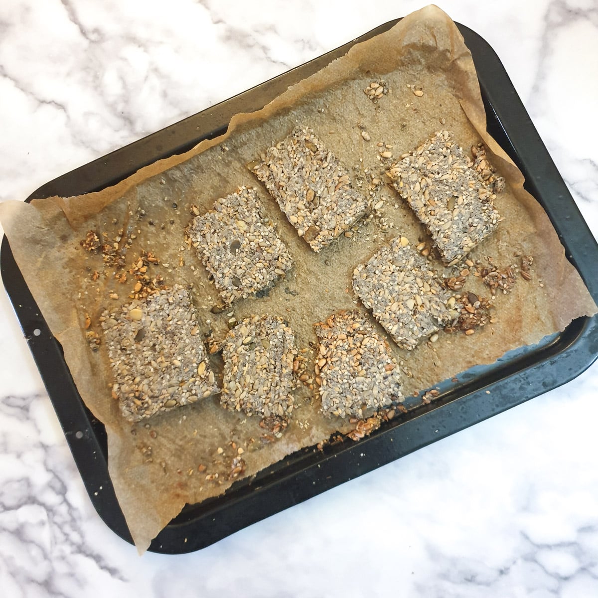 A baked tray with a few crackers that are still undercooked.