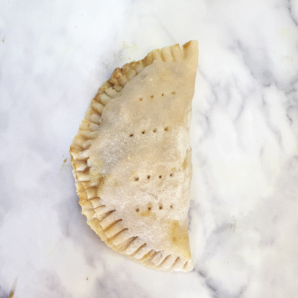 A half-moon shaped unbaked chicken curry pie.