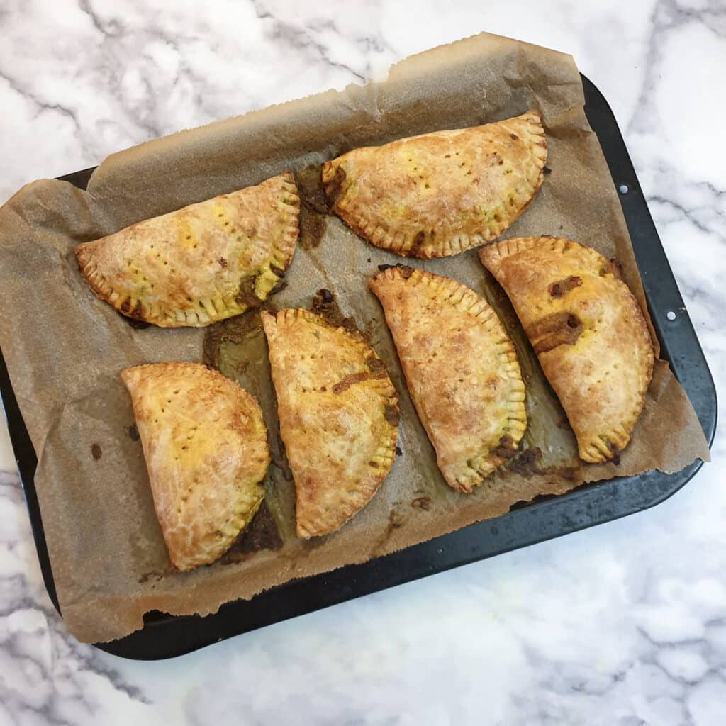 6 baked chicken curry pies on a baking tray.