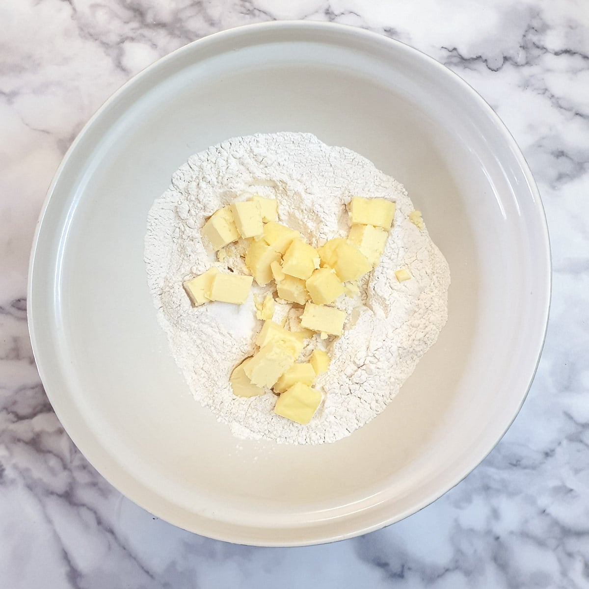 Flour and cubed butter in a mixing bowl.