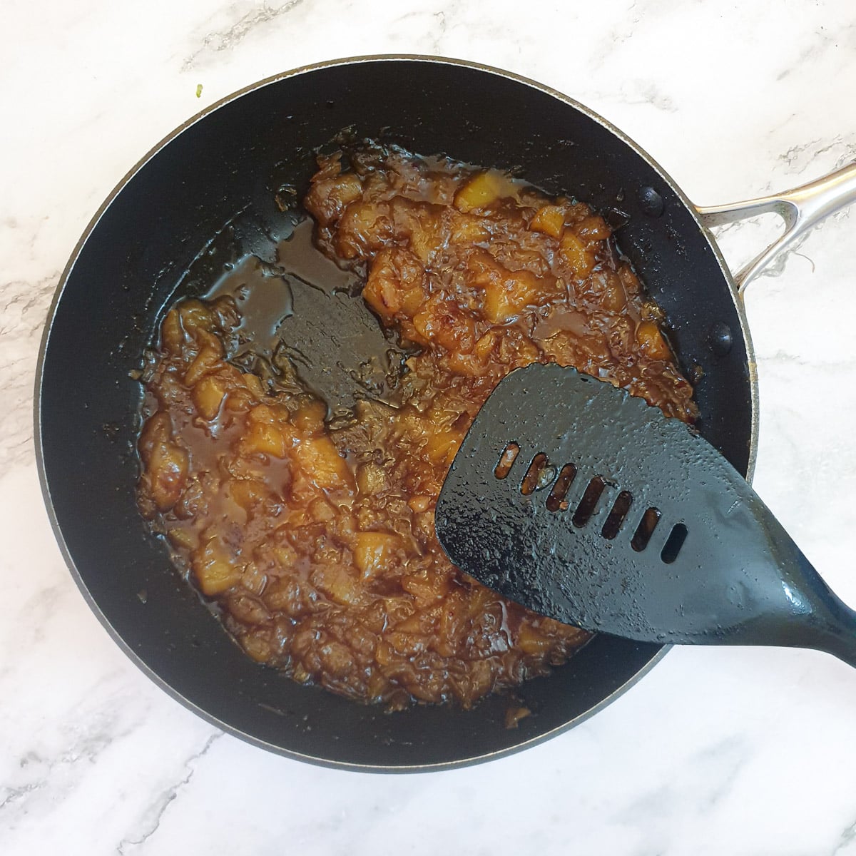 Mango chutney in a frying pan showing the trail left by a spatula.