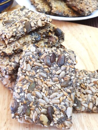 A pile of crispy seeded crackers on a wooden board.