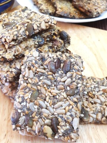 A pile of crispy seeded crackers on a wooden board.