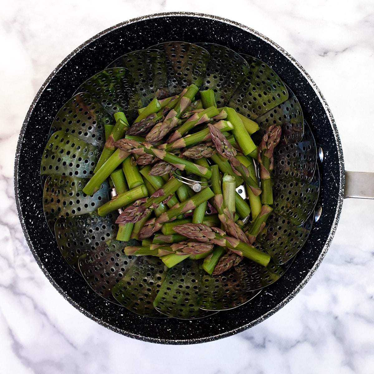 Chopped asparagus spears in a steamer basket.