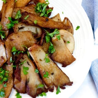 A plate of browned oyster mushrooms cooked in butter and garlic.