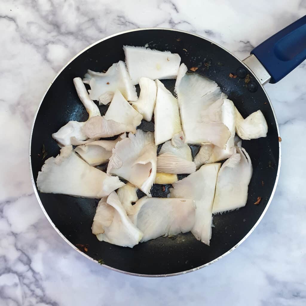 Slices of oyster mushrooms in a frying pan.
