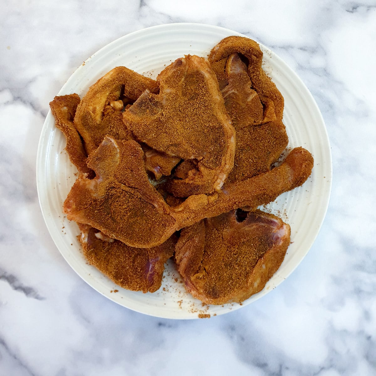 A plate of lamb chops coated with spices.