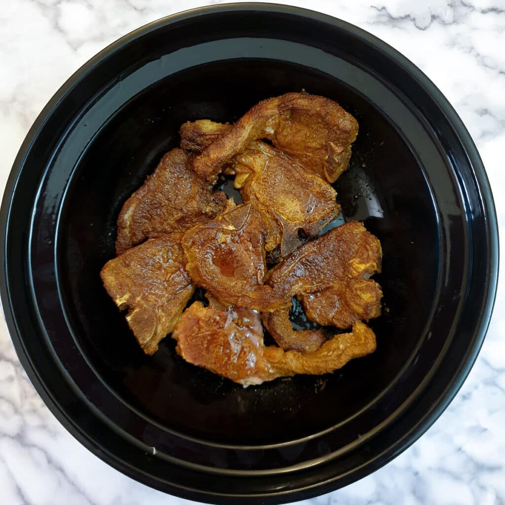 Browned lamb chops arranged in the base of a tagine.